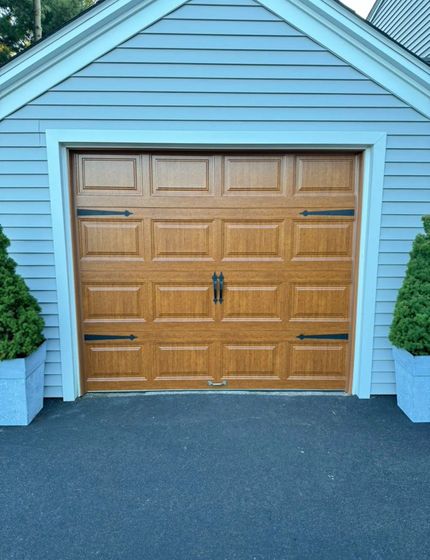 Quality Assembly Furniture & Garage Doors | A garage with a wooden door and a gray siding