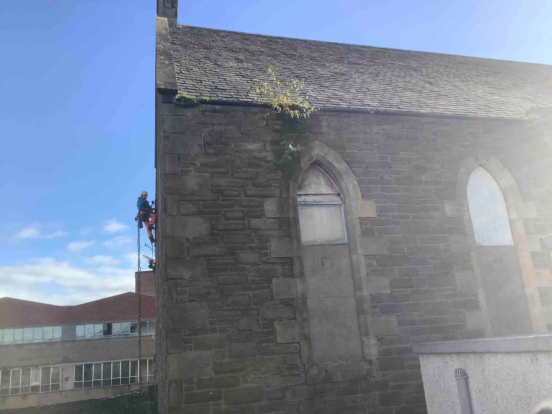 A man working as a steeplejack is climbing on top of a very tall church.