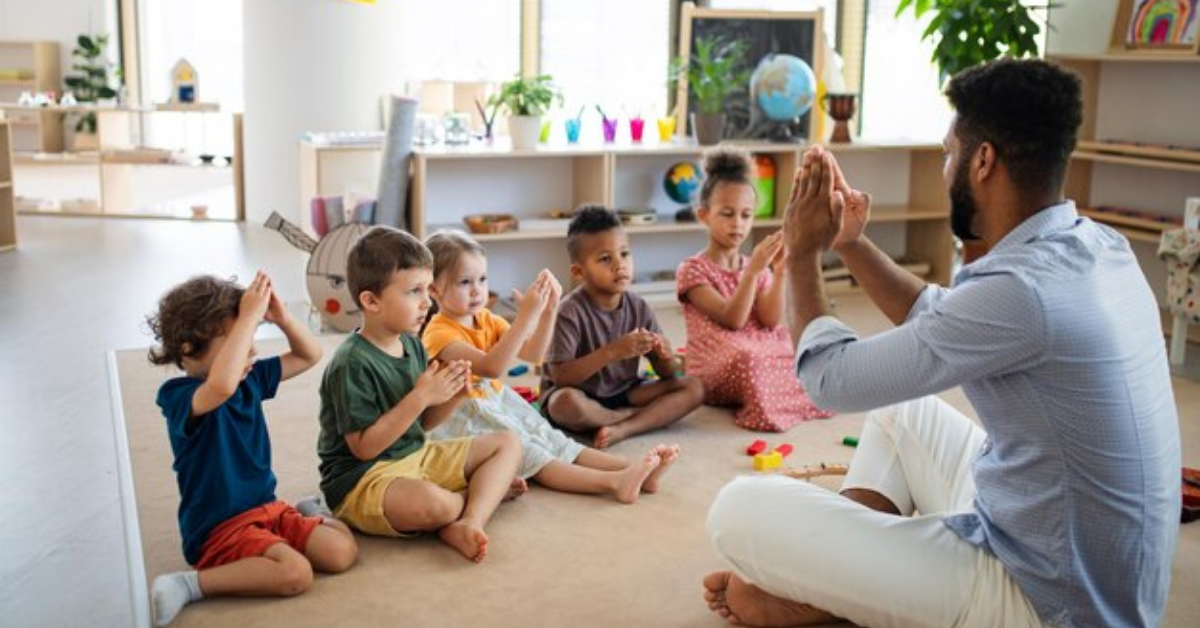A man is sitting on the floor with a group of children.