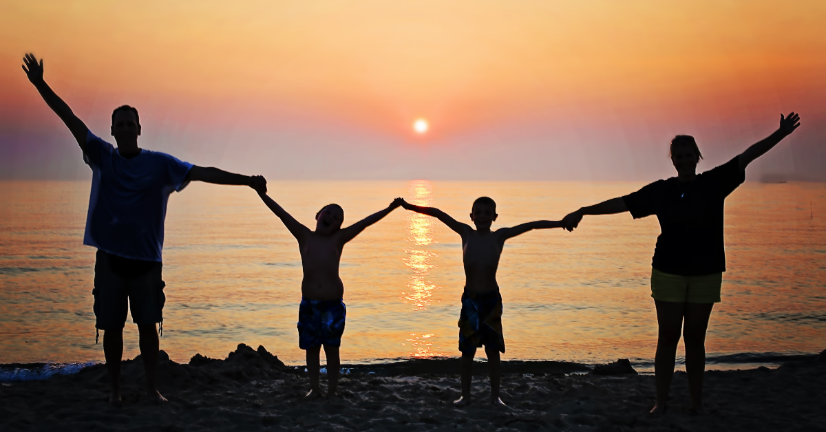 A family holding hands on the beach at sunset