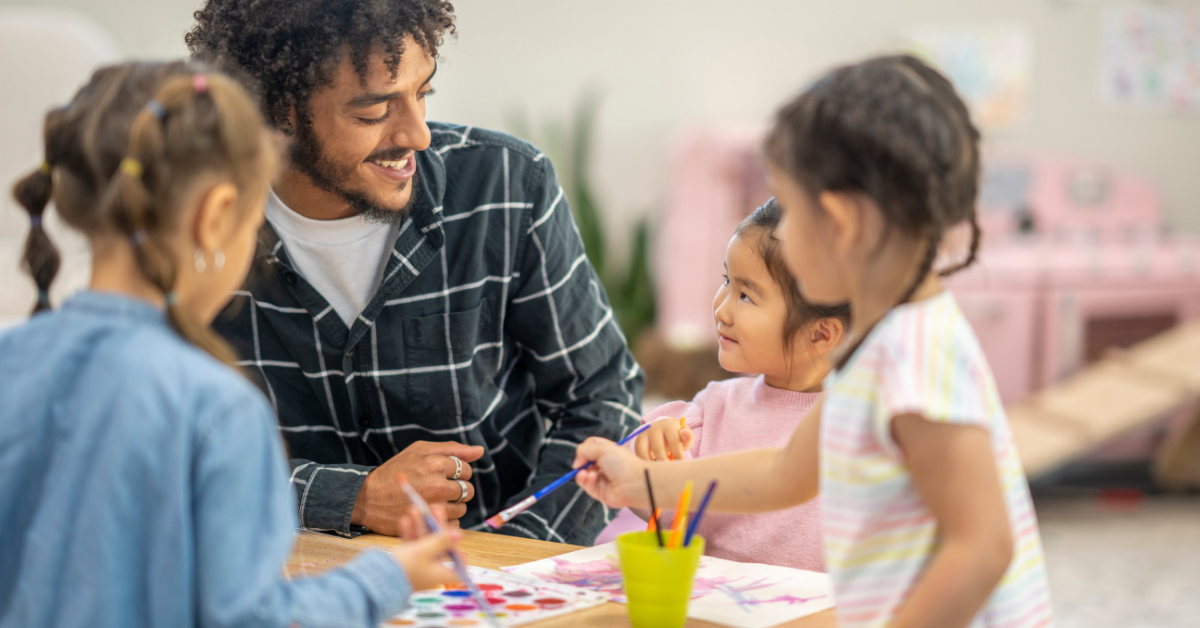 A man is sitting at a table with three little girls.