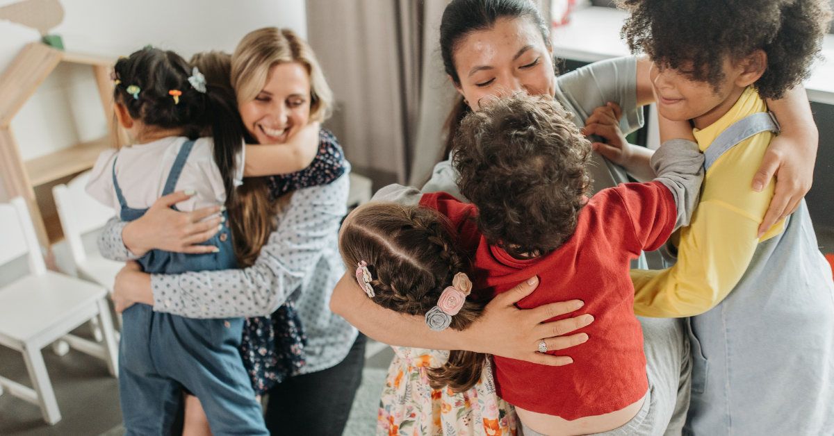 A group of women and children are hugging each other in a room.