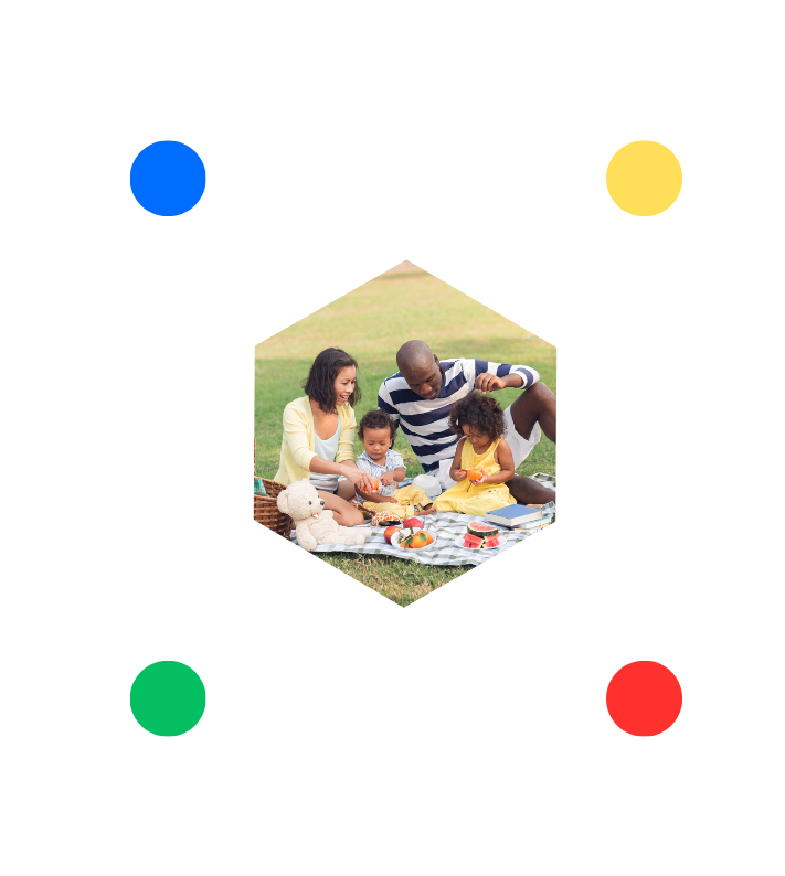 A family is sitting on a blanket in a park.