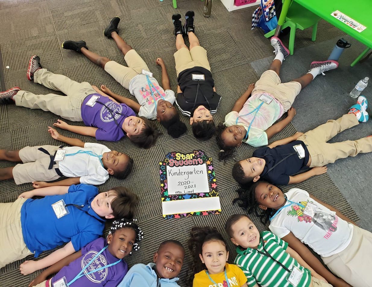 A group of children are laying in a circle on the floor