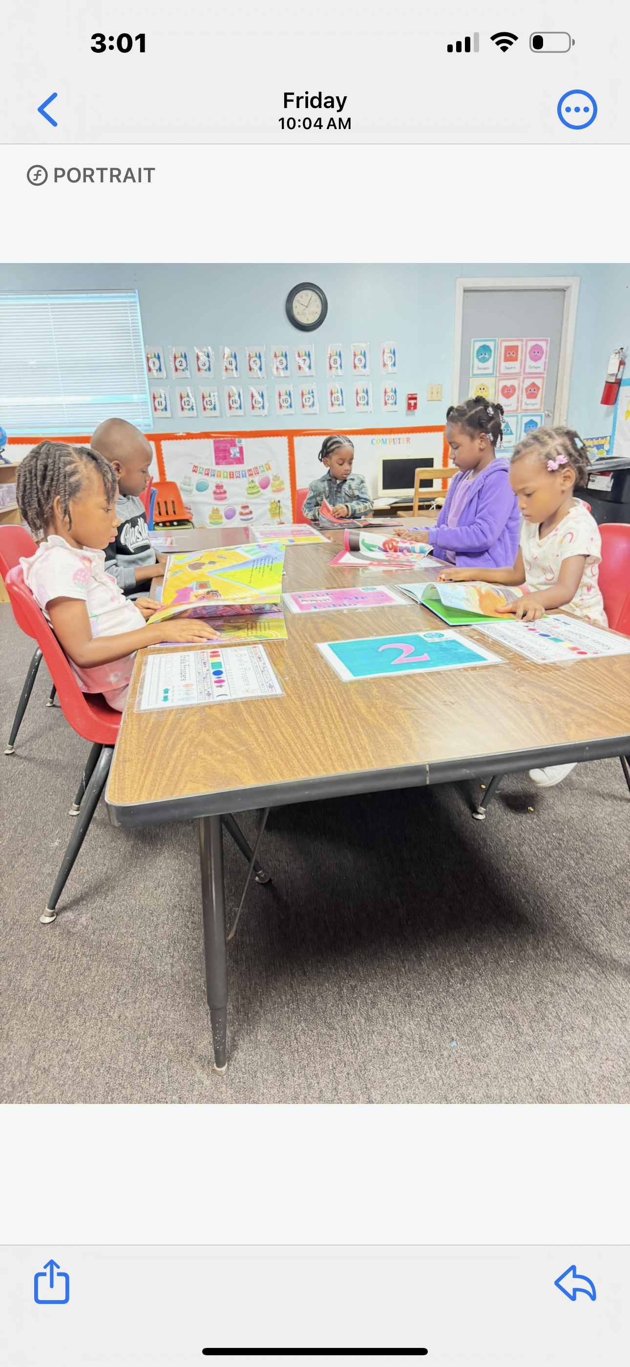 A group of children are sitting at a table in a classroom.