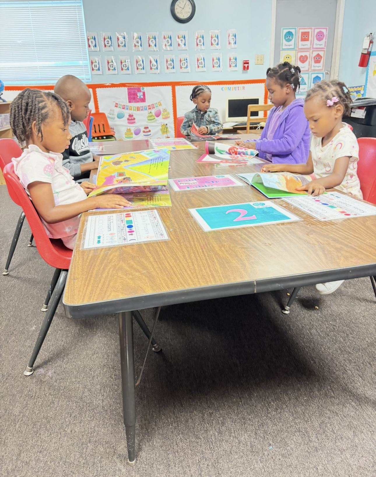 A group of children are sitting at a table in a classroom.