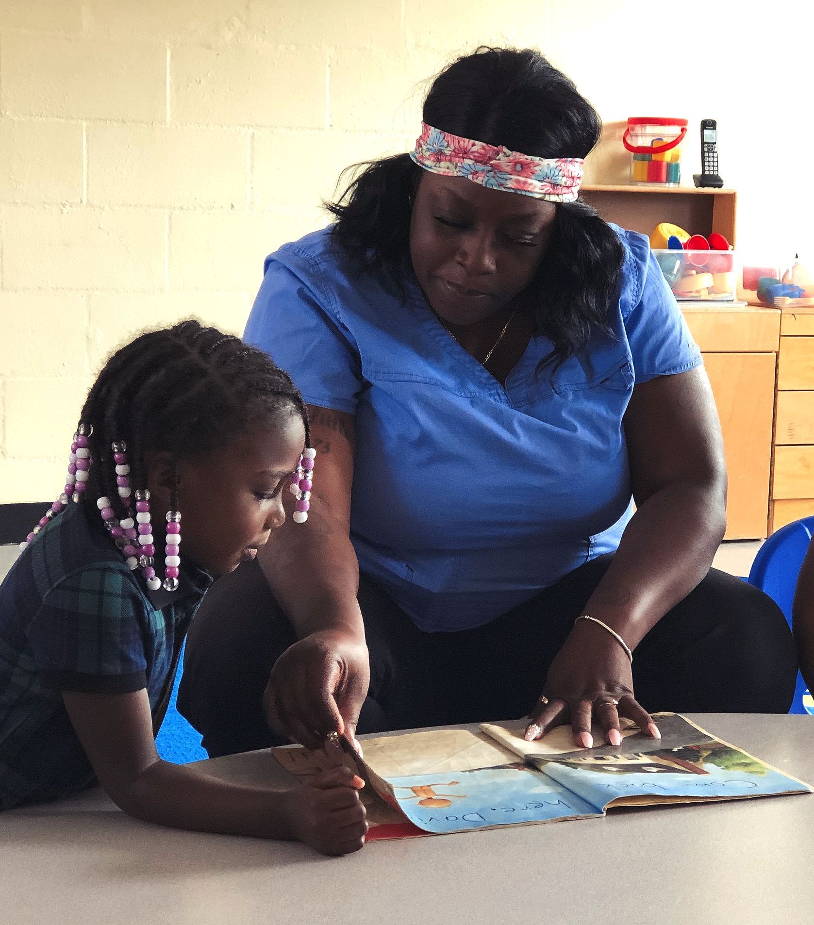A woman is reading a book to a little girl