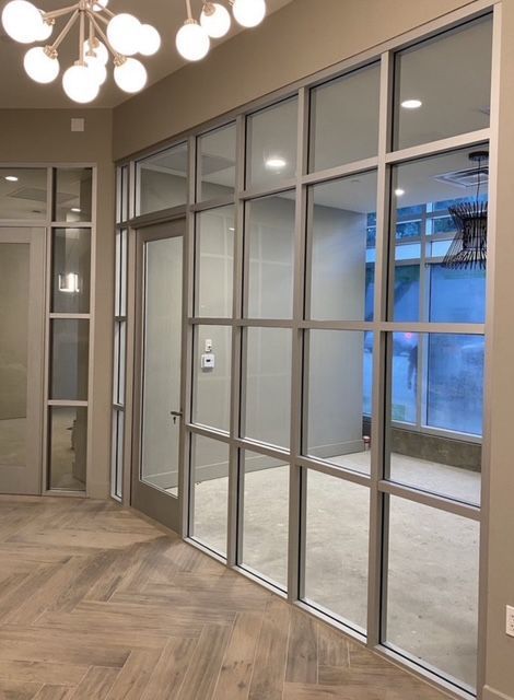 Interior space with grid-paned glass wall and door, light wood flooring, and a chandelier.