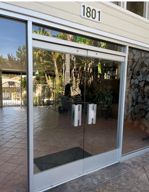 Glass door entrance with red brick wall and metallic trash cans.