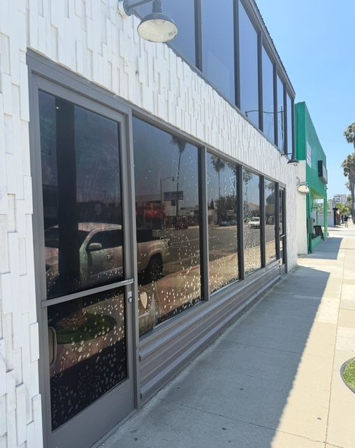 Glass building entrance with reflecting blue sky and walkways.