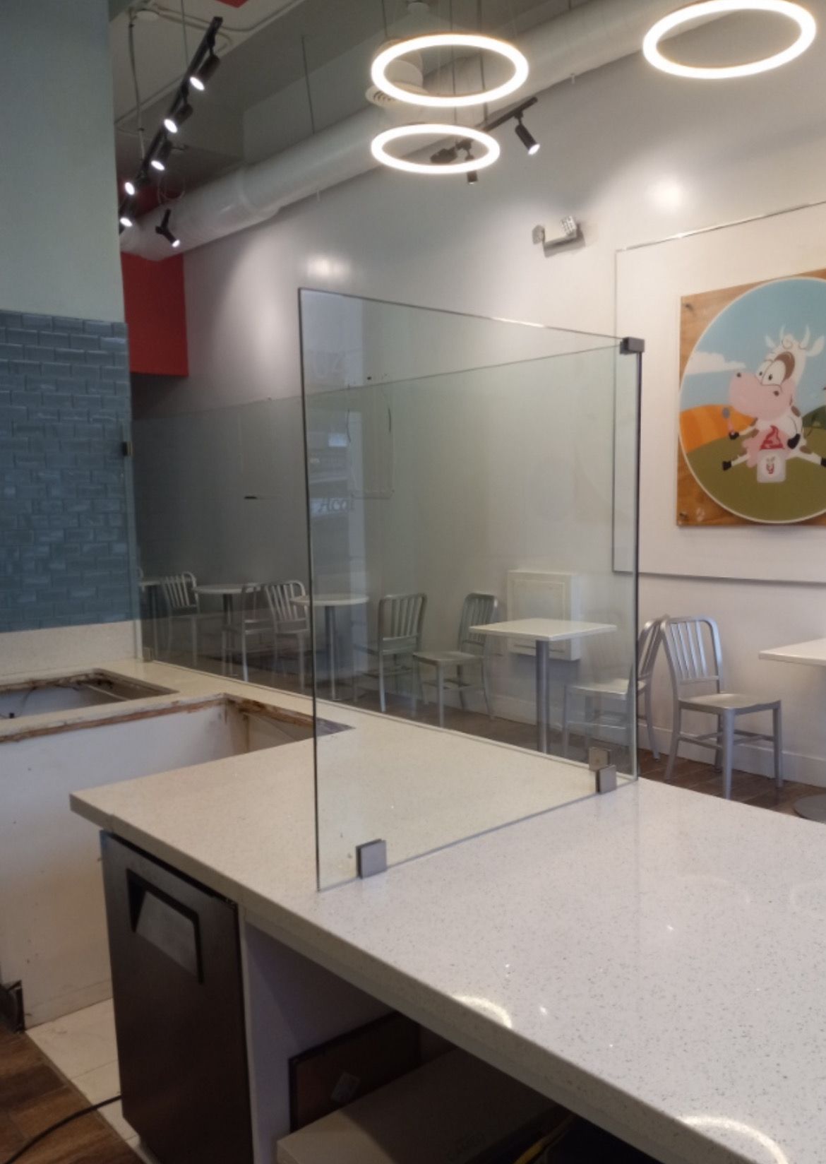 Man on ladder cleaning a large window of a building. He wears a black shirt and khaki pants. Outdoors on a sunny day.