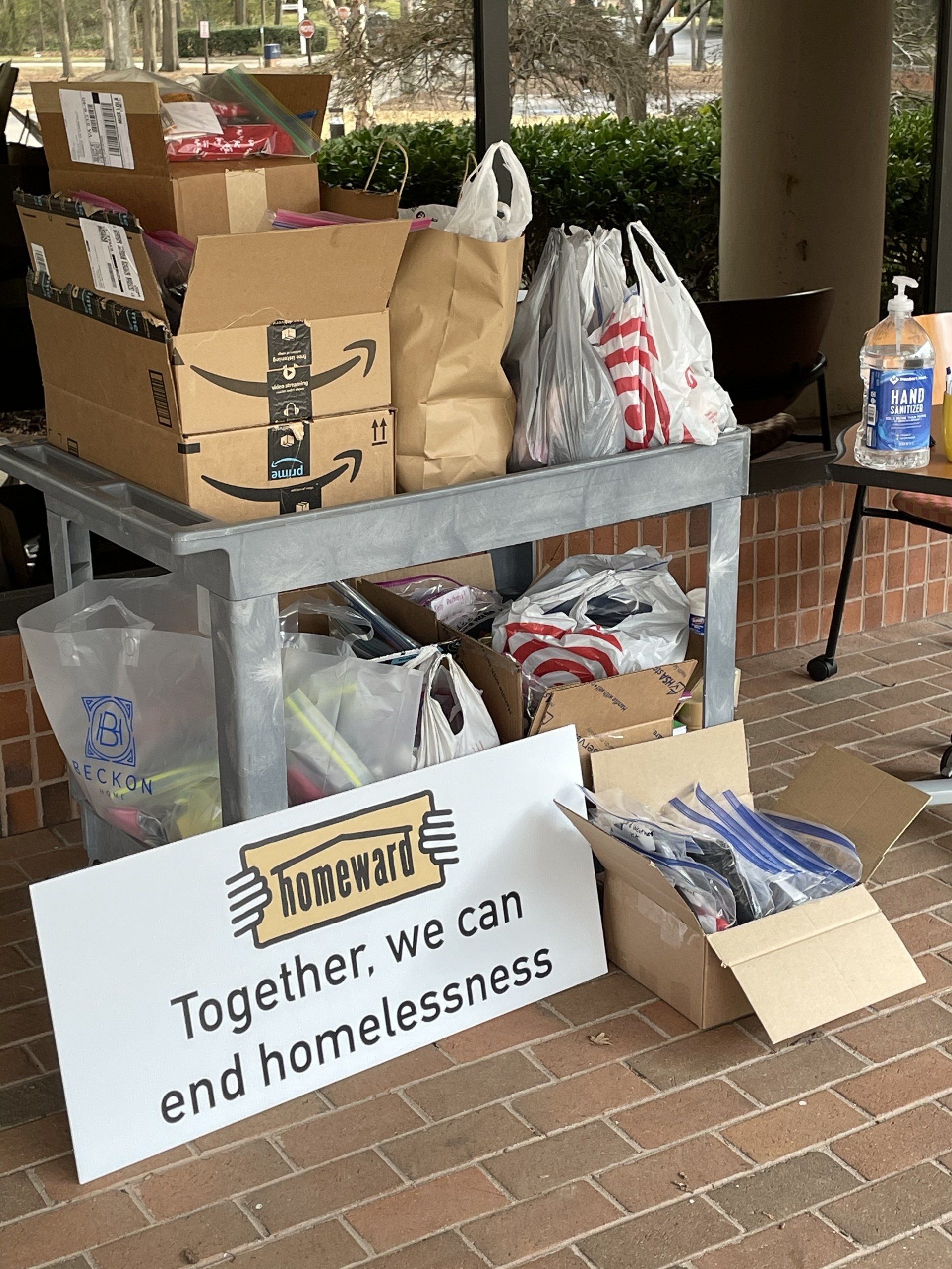 A table filled with boxes and bags and a sign that says `` together we can end homelessness ''.