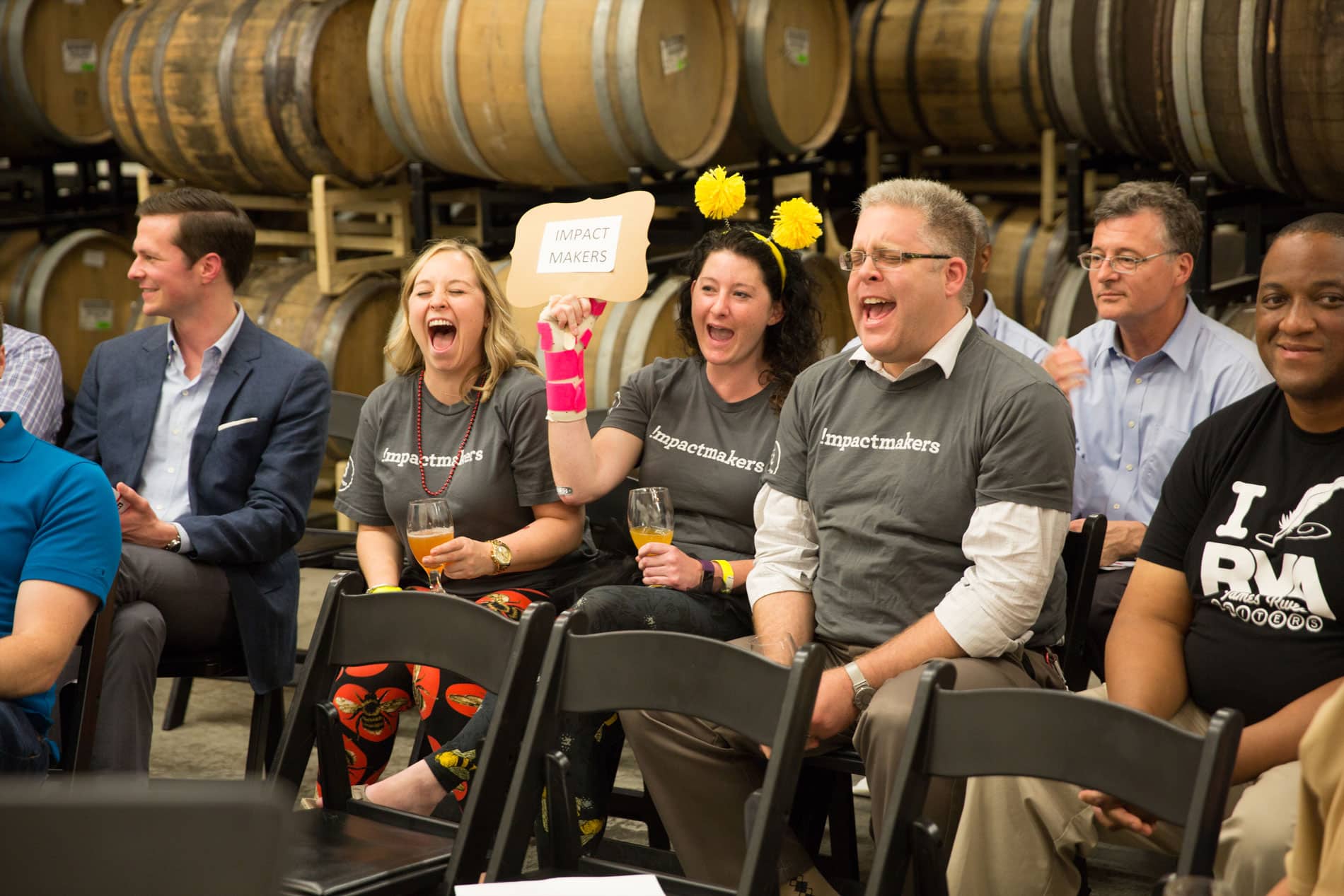 A group of people are sitting in chairs in front of barrels.