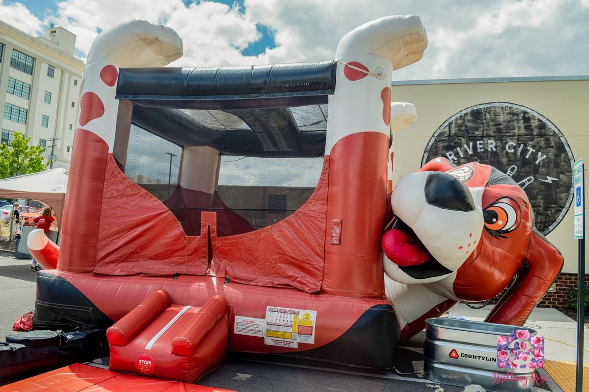 A red and white bouncy house in the shape of a dog.