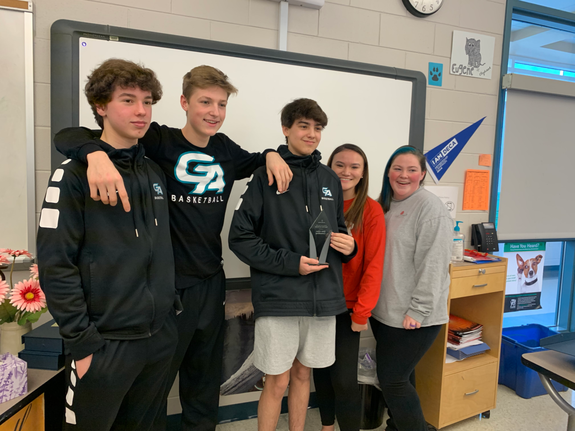 A group of young people are posing for a picture in a classroom.