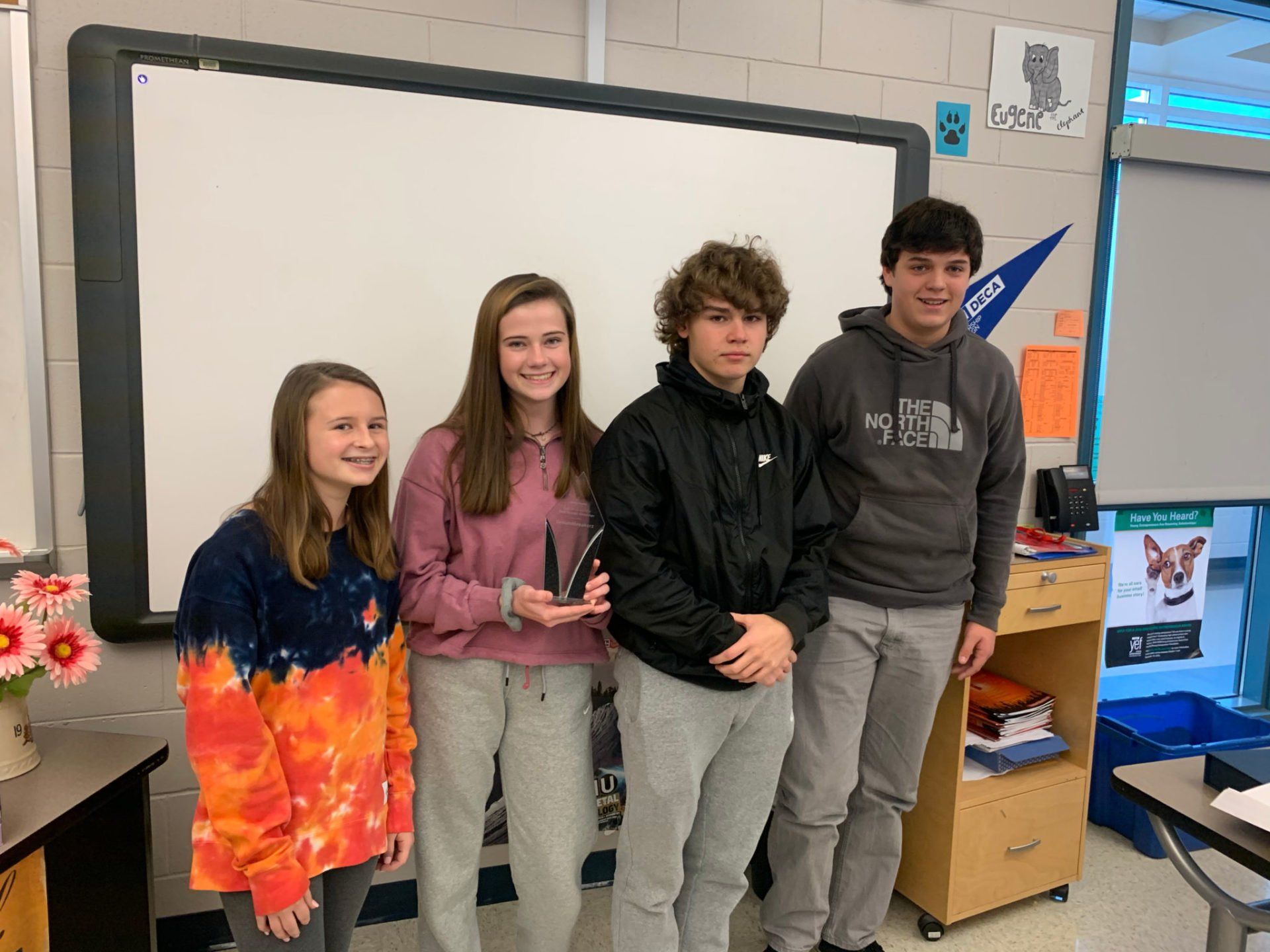 A group of young people are standing in front of a whiteboard in a classroom.