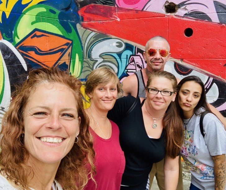 A group of people are posing for a picture in front of a graffiti wall.