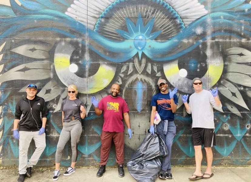 A group of people are standing in front of a mural on a wall.