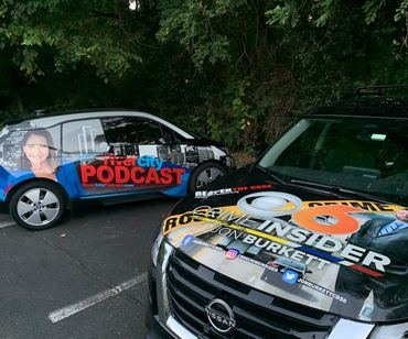 Two cars with podcast and news branding parked in a parking lot.