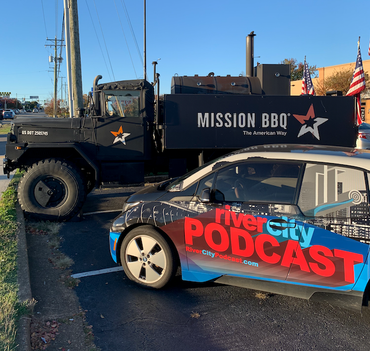 Black Mission BBQ truck next to a car with 