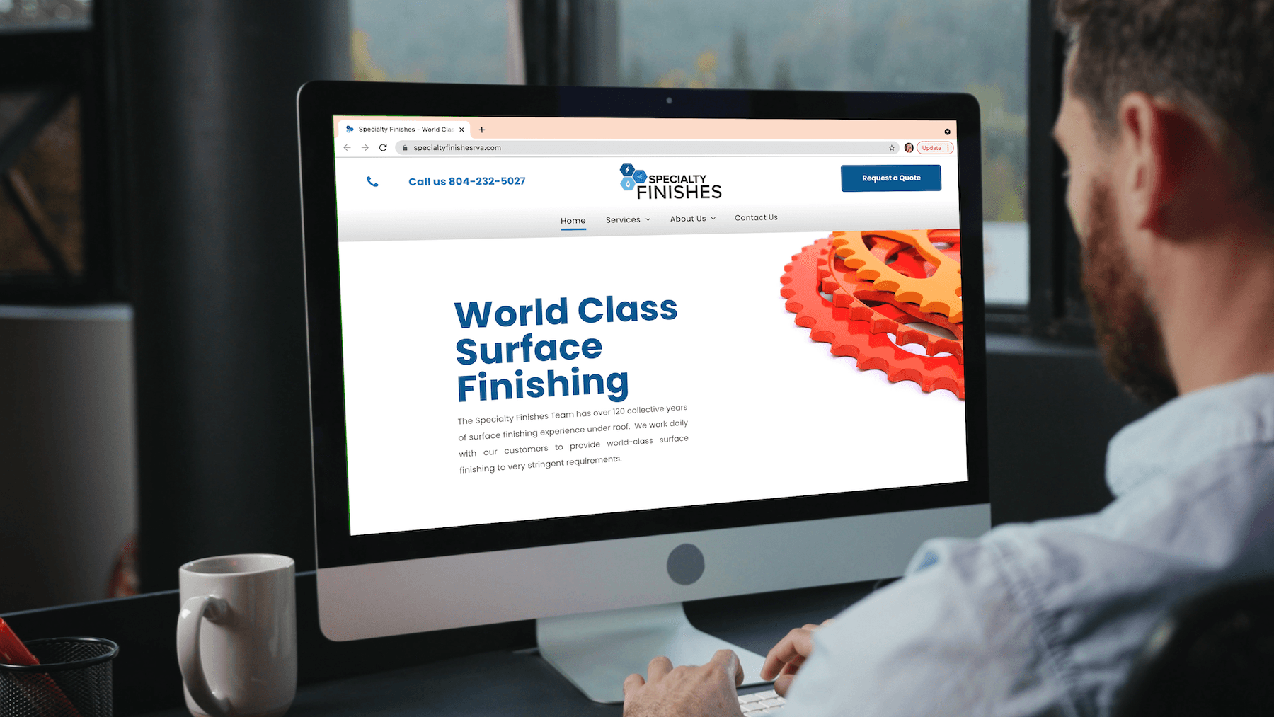 A man is sitting in front of a computer screen that says world class surface finishing
