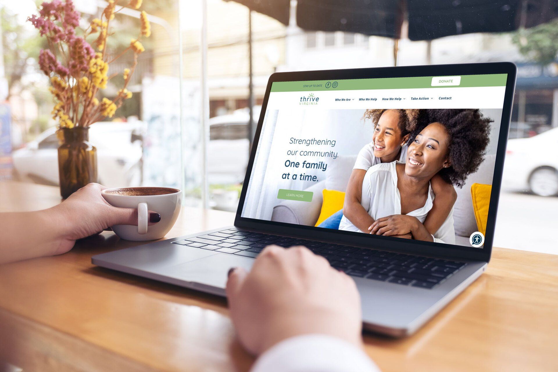 A person is sitting at a table using a laptop computer.