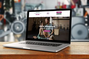 Laptop displaying a website about band movement, set on a wooden table in a gym.