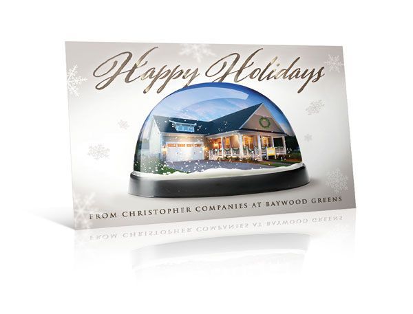 A happy holidays card with a house in a snow globe