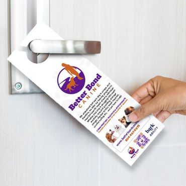 Hand placing a door hanger for Better Bond Canine on a door handle.