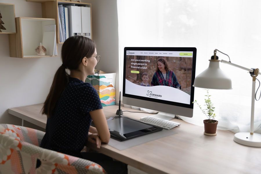 A woman is sitting at a desk looking at a computer screen.