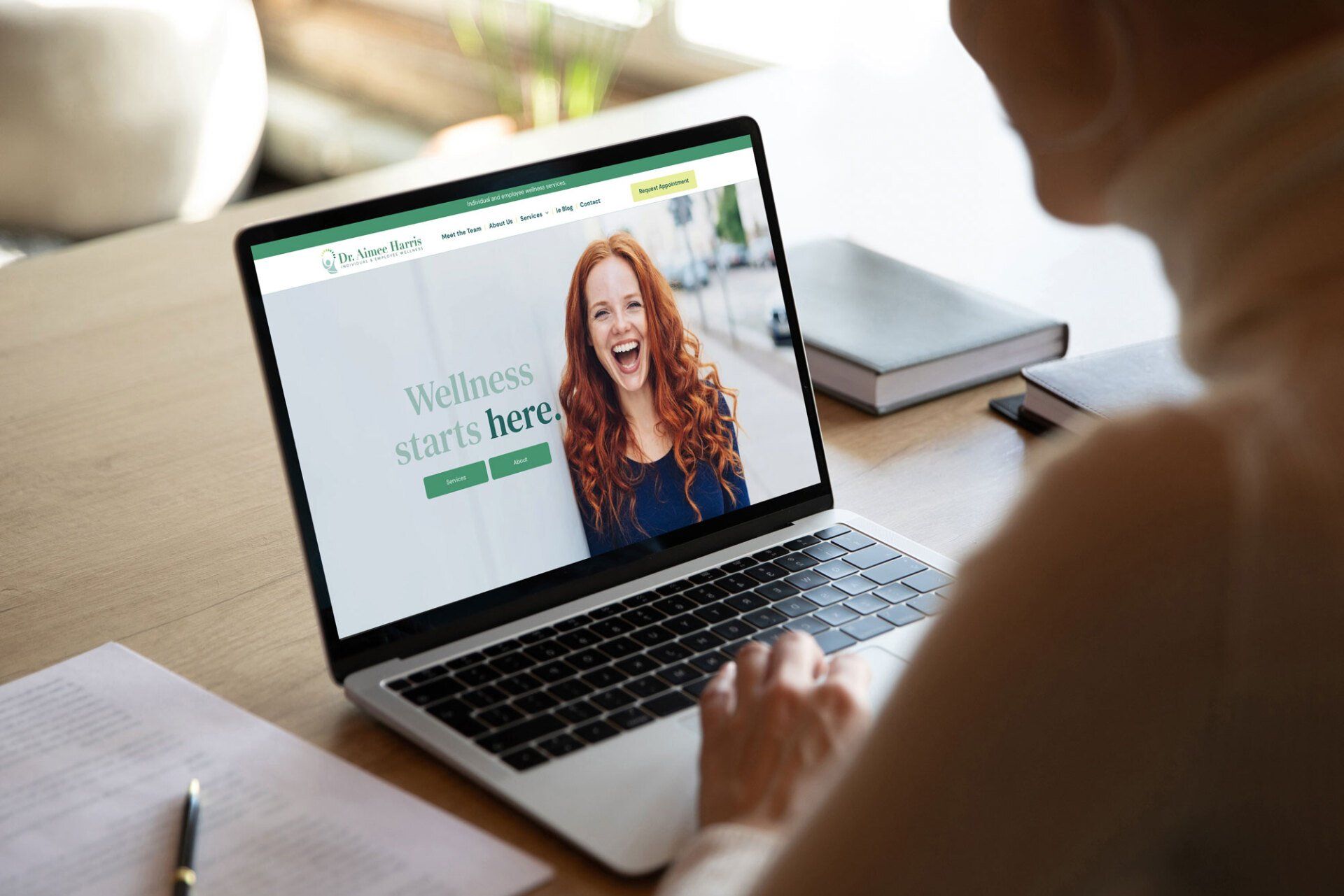A woman is sitting at a desk using a laptop computer.
