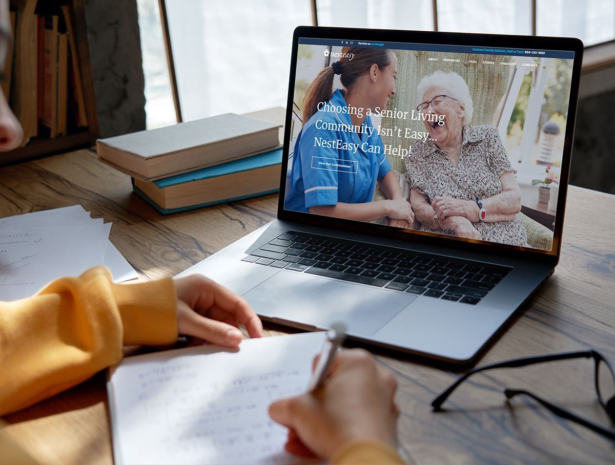 a person is writing on a piece of paper in front of a laptop computer