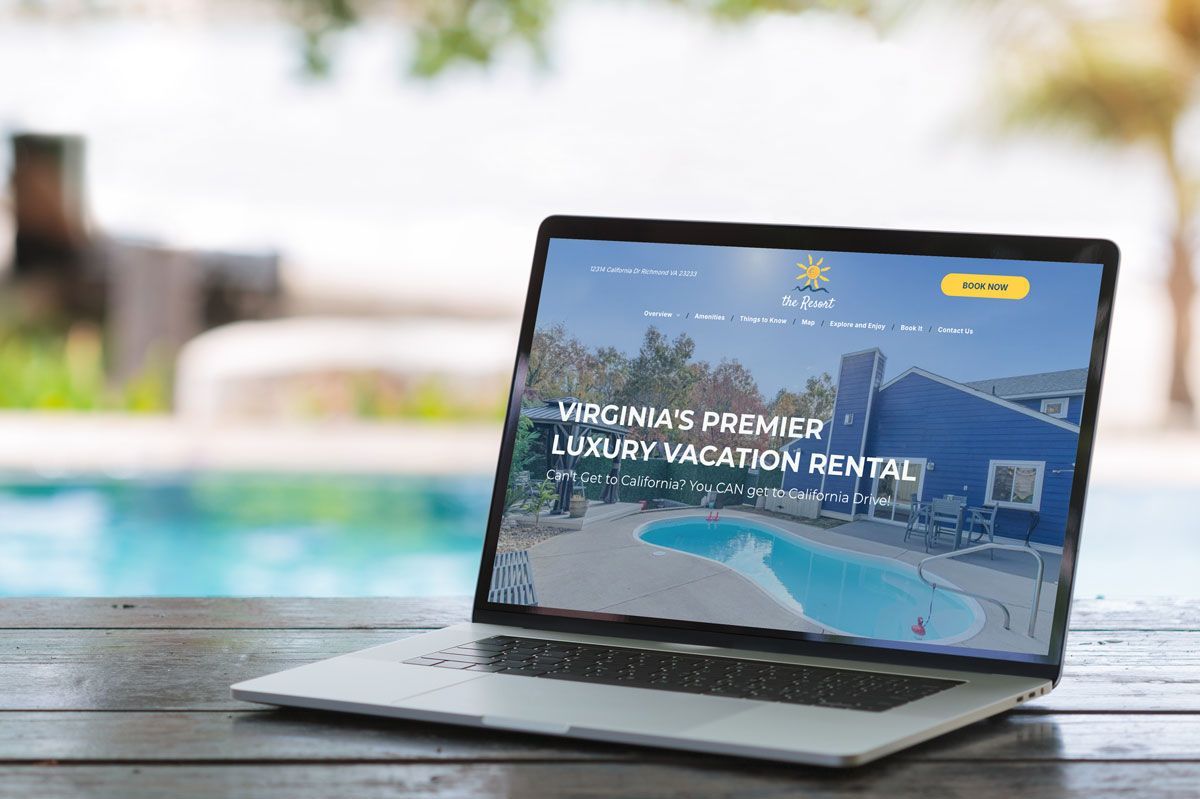 A laptop computer is sitting on a wooden table next to a pool.