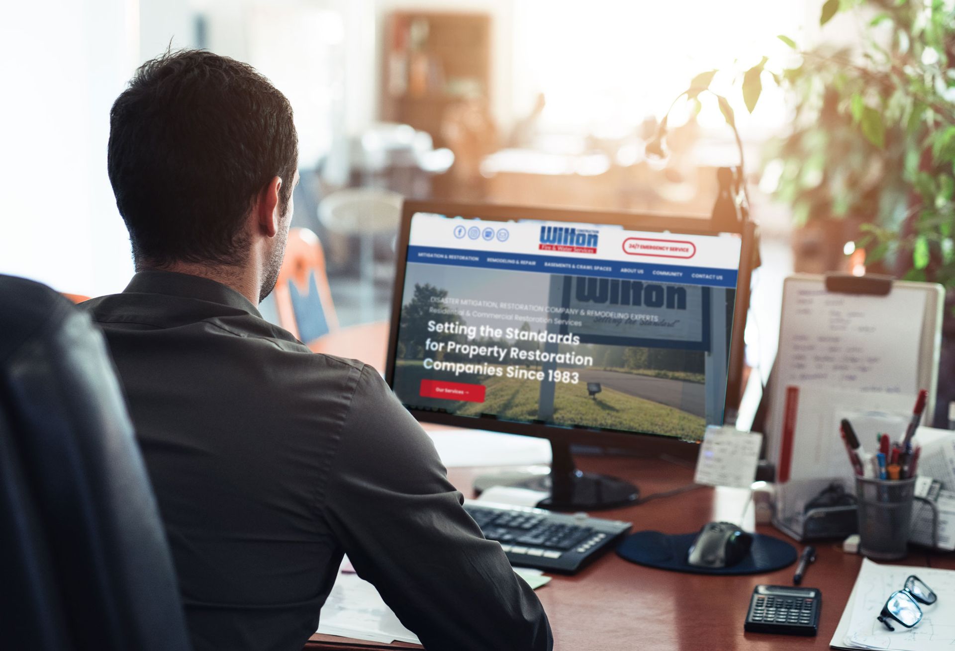 a man is sitting at a desk looking at a computer screen