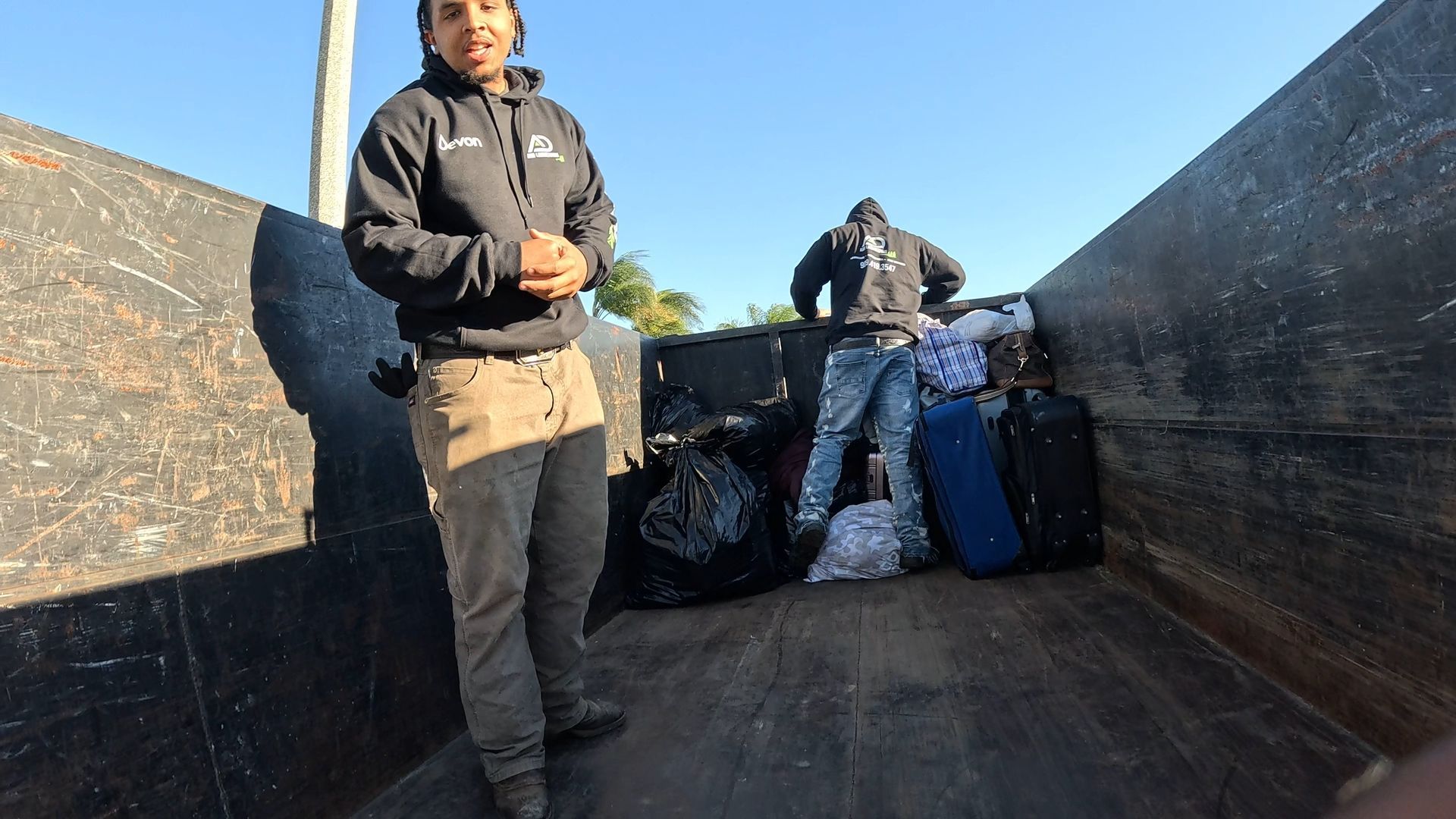 A&D Junk Removal helping a mother with trash and clothing; clear sky.