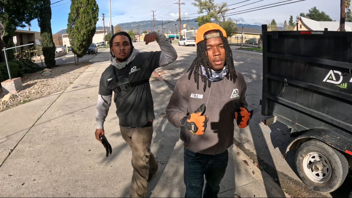 A&D Crew walking toward the camera, one flexing, next to our trailer on a street.