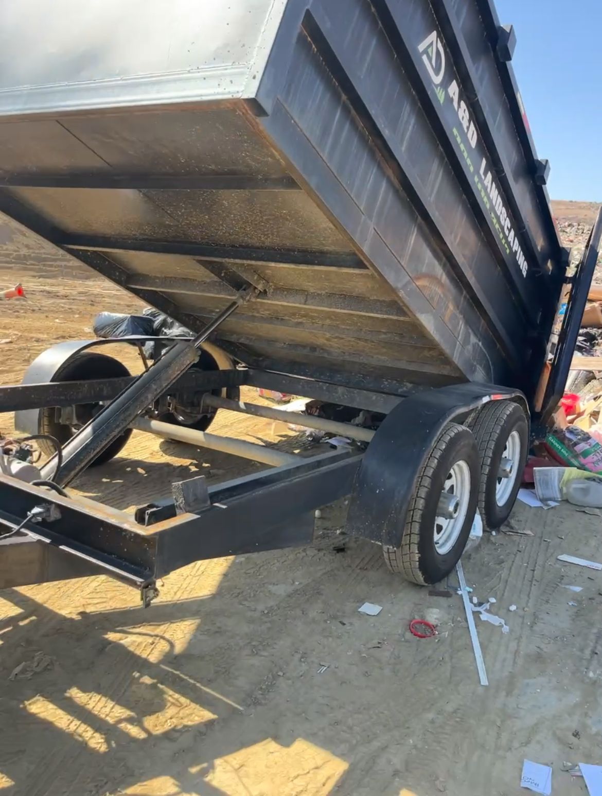 A&D dump trailer with the bed raised, on a dirt surface.