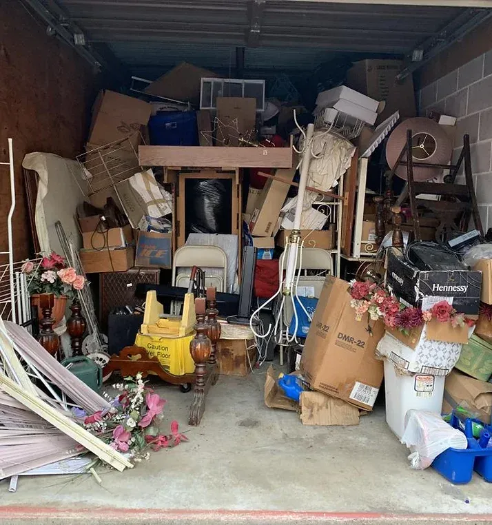 A storage unit overflowing with various items, including boxes, furniture, and decorations.