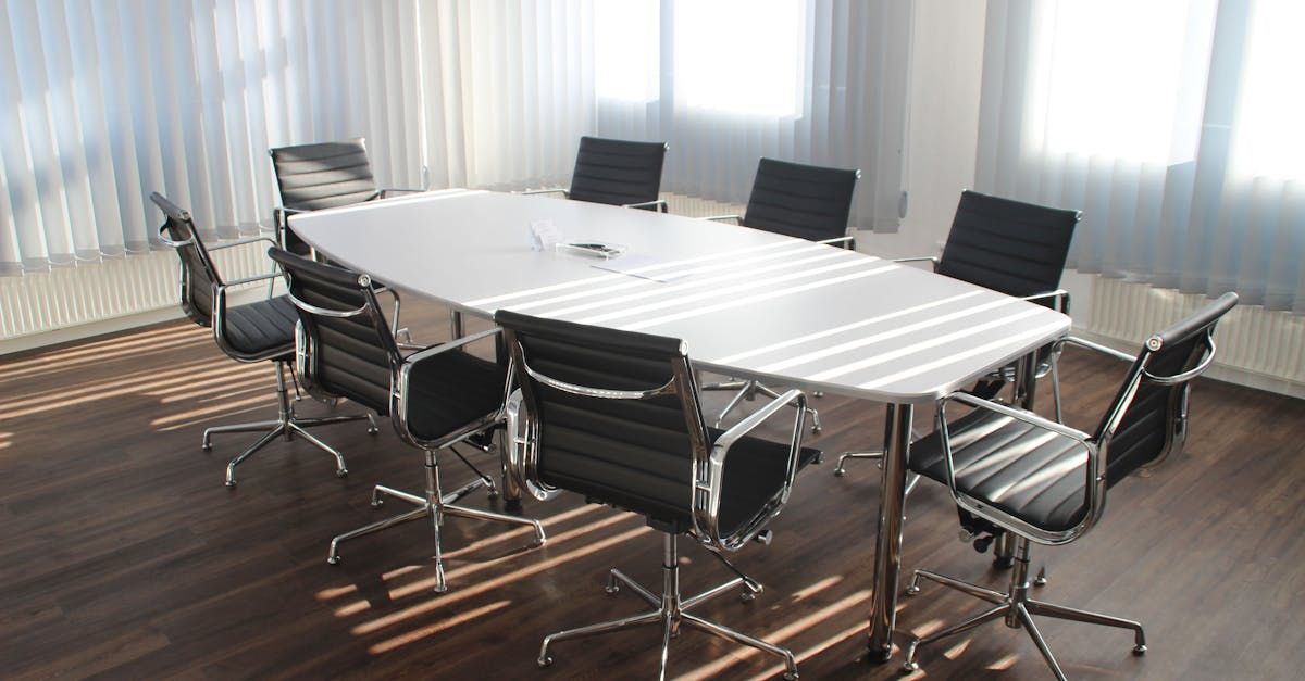 Conference room with a large white table and black leather chairs.