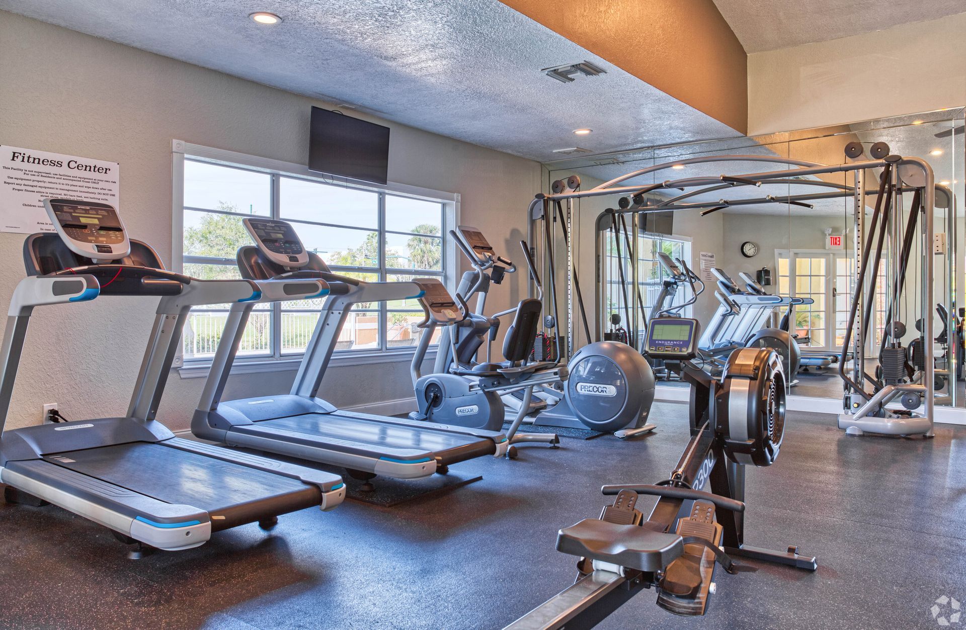 Gym interior with treadmills, elliptical, rowing machine, and weight machines.