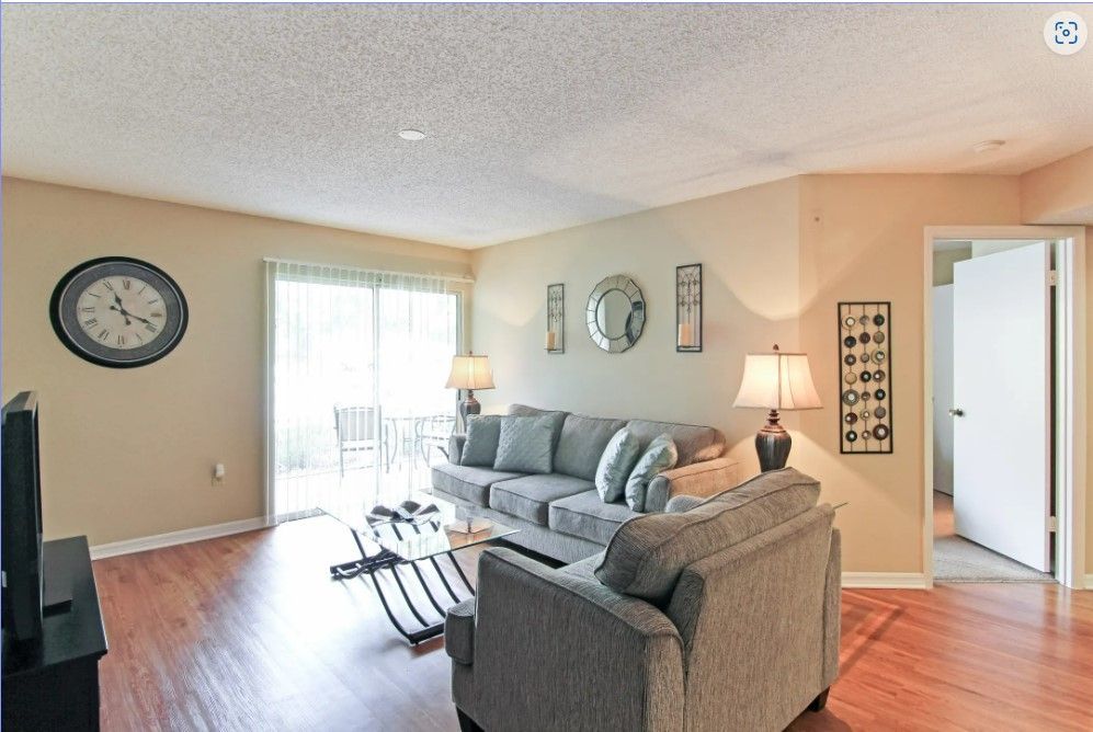 Living room with gray sofa, clock, and sliding glass door to patio.