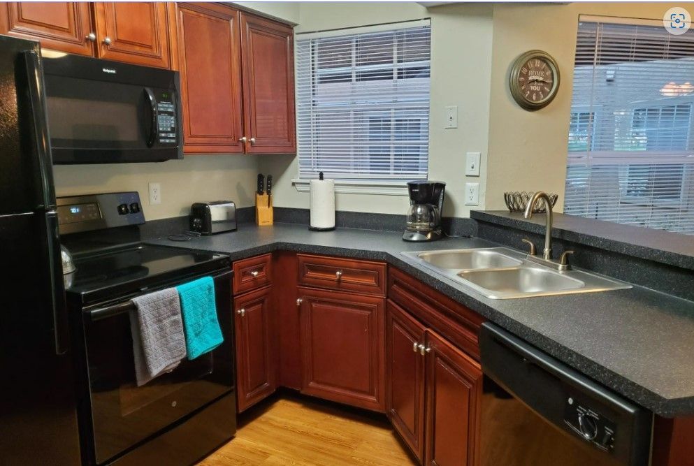 Kitchen with black appliances, dark brown cabinets, and a gray countertop.