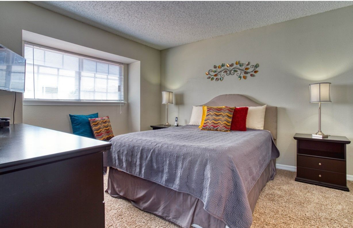 Bedroom with a bed, nightstands, window, and decorative wall art.