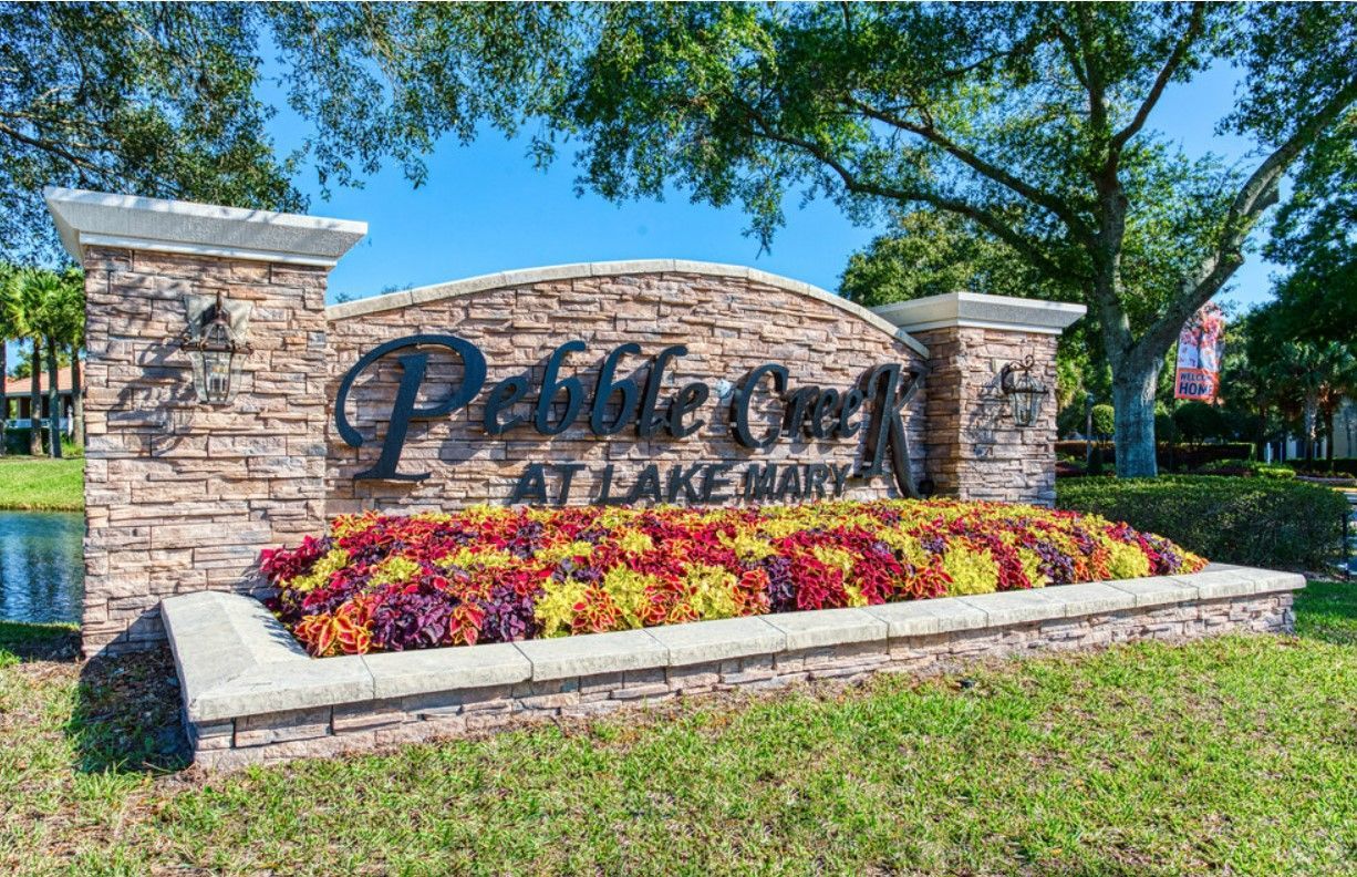Sign for Pebble Creek at Lake Clarke, stone and concrete with colorful flowers.