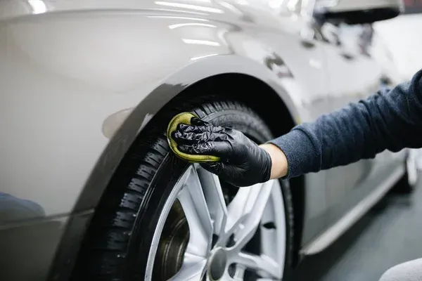 An automobile detailing expert performs car detailing on the tires of a vehicle parked in Austin.