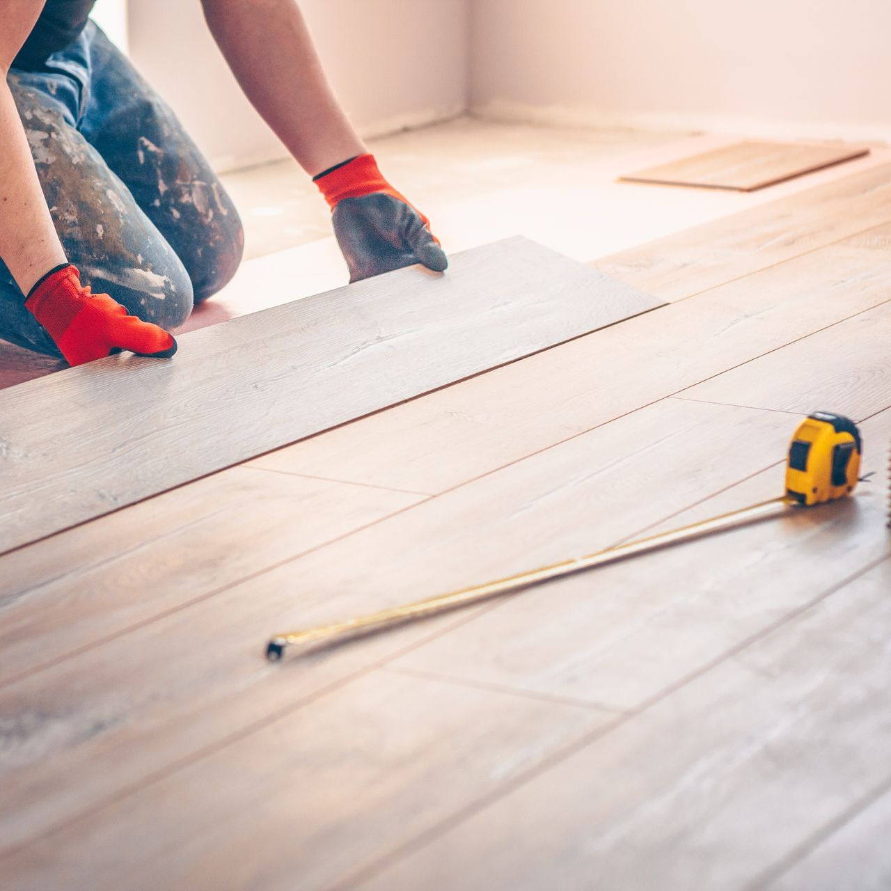 A person is measuring a wooden floor with a tape measure.