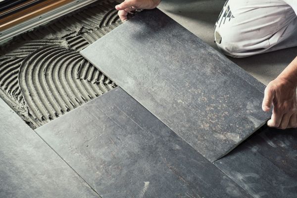 A person is laying a tile on the floor.