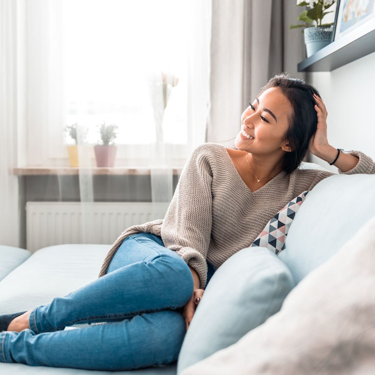 A woman is sitting on a couch with her legs crossed and smiling.