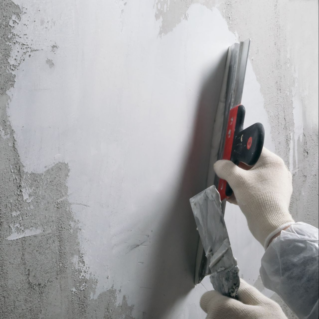 A person is plastering a wall with a spatula.