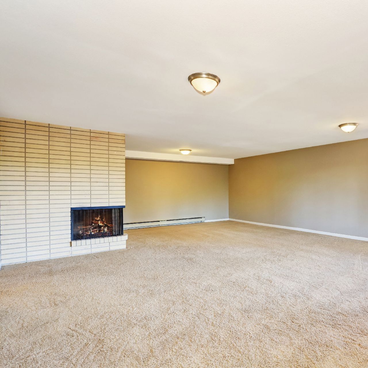 An empty living room with a fireplace and carpet